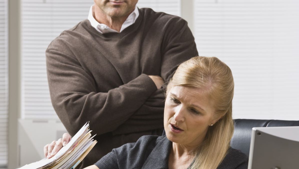 micromanaging: businessman looking over employee's shoulder