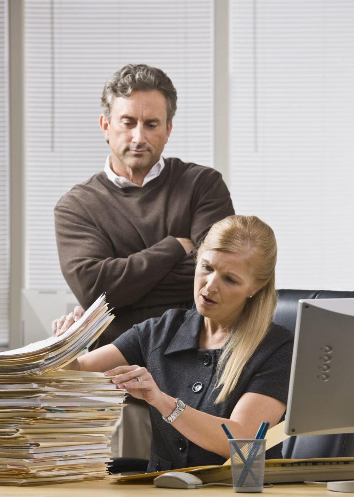 micromanaging: businessman looking over employee's shoulder