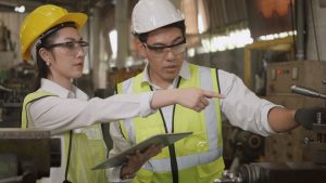 two people in a factory looking at equipment