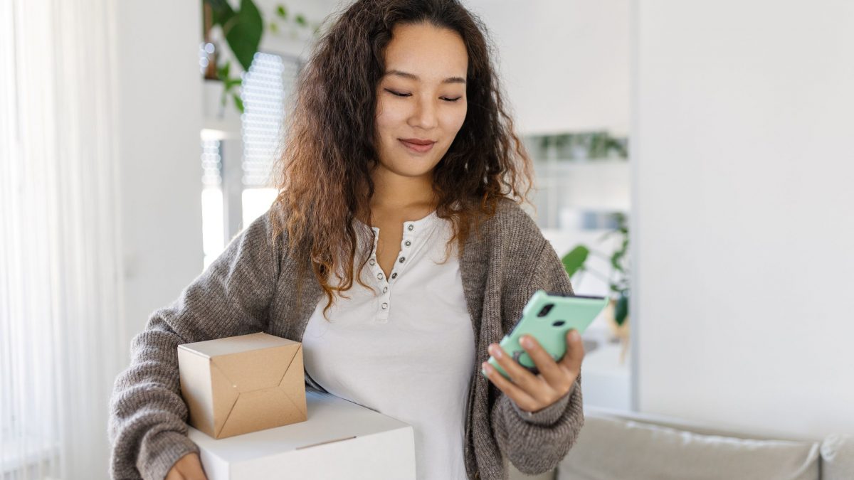 woman holding packages and looking at mobile phone