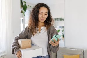 woman holding packages and looking at mobile phone